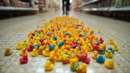 make a picture of very tiny toy colorful ducks spilled on the ground in a target and someone w...jpg