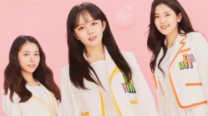 The female members of the group TEAPARTY alongside a pink background. They wear bright clothing. They are standing in a line facing front. From left to right, its Hyunji, Maha and then Ria. Above the members, there is the group logo ‘TEA PARTY’ in a fancy white design. There is also pink bubbles all around the members.