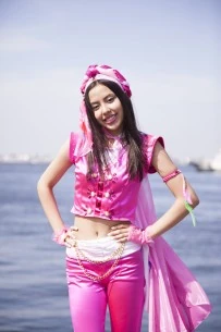 sayuri stood in front of the ocean with her hands on her hips. she is wearing a pink outfit